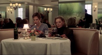 Movie still from “Birth” (2004), directed by Jonathan Glazer – Two women are sitting at a table in front of a glass of red wine; Medium shot, High angle