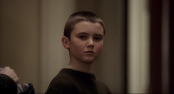 Movie still from “Birth” (2004), directed by Jonathan Glazer – A young boy is looking into the camera; Close Up shot, Over the shoulder angle