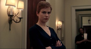 Movie still from “Birth” (2004), directed by Jonathan Glazer – A woman standing in a room with her arms crossed; Close Up shot, Low angle