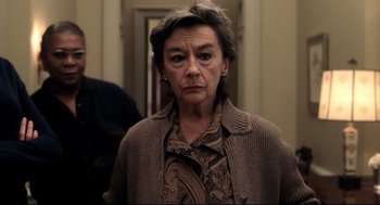 Movie still from “Birth” (2004), directed by Jonathan Glazer – An older woman in a brown sweater looking at the camera; Close Up shot, Over the shoulder angle