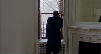 Movie still from “Birth” (2004), directed by Jonathan Glazer – A man standing in front of an open window looking outside; Medium shot, Over the shoulder angle