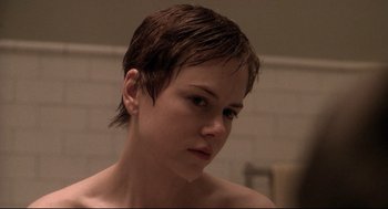 Movie still from “Birth” (2004), directed by Jonathan Glazer – A young woman with short brown hair is looking at the camera; Close Up shot, Over the shoulder angle