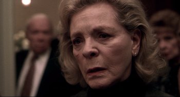 Movie still from “Birth” (2004), directed by Jonathan Glazer – An older woman with blonde hair and a black shirt; Close Up shot, Over the shoulder angle