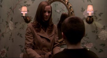 Movie still from “Birth” (2004), directed by Jonathan Glazer – A woman in a brown coat looking at a man in front of a mirror; Medium shot, Over the shoulder angle