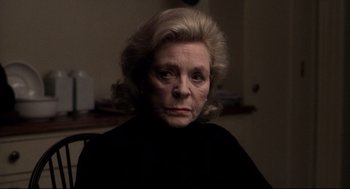 Movie still from “Birth” (2004), directed by Jonathan Glazer – An older woman with blonde hair wearing a black shirt; Close Up shot, Over the shoulder angle
