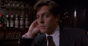 Movie still from “Bitter Moon” (1992), directed by Roman Polanski – A man wearing a suit and tie sitting in front of a bar; Close Up shot, High angle