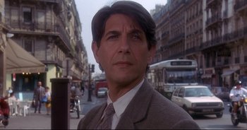 Movie still from “Bitter Moon” (1992), directed by Roman Polanski – A person wearing a suit on a city street; Close Up shot, Low angle