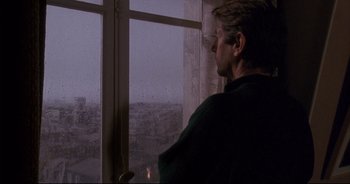 Movie still from “Bitter Moon” (1992), directed by Roman Polanski – A man standing in front of a window looking outside; Medium shot, Over the shoulder angle