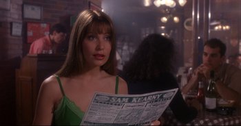 Movie still from “Bitter Moon” (1992), directed by Roman Polanski – A woman in a green top holding a newspaper; Close Up shot, Over the shoulder angle