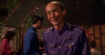 Movie still from “Bitter Moon” (1992), directed by Roman Polanski – A man in a purple shirt smiling for the camera; Close Up shot, Low angle