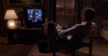 Movie still from “Bitter Moon” (1992), directed by Roman Polanski – A man sitting in front of a tv in a living room; Wide shot, High angle