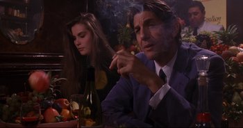 Movie still from “Bitter Moon” (1992), directed by Roman Polanski – A man smoking a cigarette in front of a woman; Medium shot, Over the shoulder angle