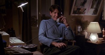 Movie still from “Bitter Moon” (1992), directed by Roman Polanski – A man sitting at a table talking on a phone; Medium shot, Low angle