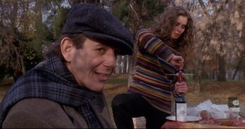 Movie still from “Bitter Moon” (1992), directed by Roman Polanski – A man and a woman sitting in the grass; Medium shot, High angle