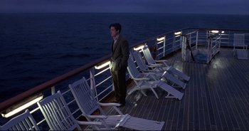 Movie still from “Bitter Moon” (1992), directed by Roman Polanski – A man standing on a deck of a boat at night; Wide shot, High angle