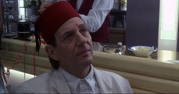 Movie still from “Bitter Moon” (1992), directed by Roman Polanski – A man with a red hat sitting in a booth; Close Up shot, Over the shoulder angle
