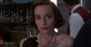 Movie still from “Bitter Moon” (1992), directed by Roman Polanski – A woman in pearls holding a glass of water; Close Up shot, Over the shoulder angle