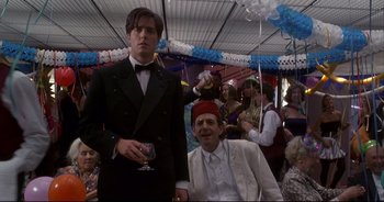 Movie still from “Bitter Moon” (1992), directed by Roman Polanski – A man in a suit and a man in a red hat; Medium shot, Low angle