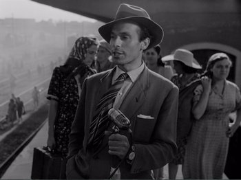 Movie still from “Bitter Rice” (1949), directed by Giuseppe De Santis – A black and white photo of a man in a suit and tie; Medium shot, Low angle