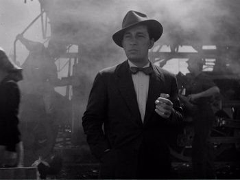 Movie still from “Bitter Rice” (1949), directed by Giuseppe De Santis – A black and white photo of a man smoking a cigarette; Medium shot, Low angle