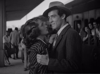 Movie still from “Bitter Rice” (1949), directed by Giuseppe De Santis – A man and a woman embracing each other in front of a crowd; Medium shot, Low angle