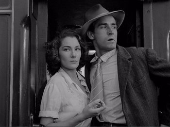 Movie still from “Bitter Rice” (1949), directed by Giuseppe De Santis – A man and a woman standing next to each other in front of a door; Medium shot, Low angle