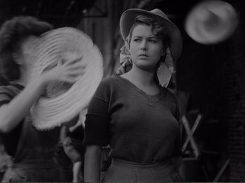Movie still from “Bitter Rice” (1949), directed by Giuseppe De Santis – A black and white photo of a woman wearing a hat; Medium shot, Over the shoulder angle