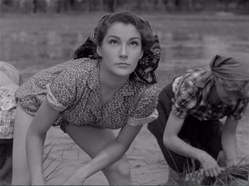 Movie still from “Bitter Rice” (1949), directed by Giuseppe De Santis – A woman crouching down next to another woman; Medium shot, Low angle