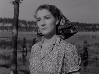 Movie still from “Bitter Rice” (1949), directed by Giuseppe De Santis – A woman with a head scarf is posing for a picture; Medium shot, Low angle