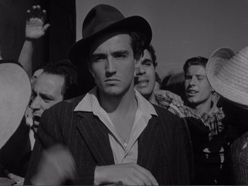 Movie still from “Bitter Rice” (1949), directed by Giuseppe De Santis – Black and white photograph of a man in a crowd; Medium shot, Low angle