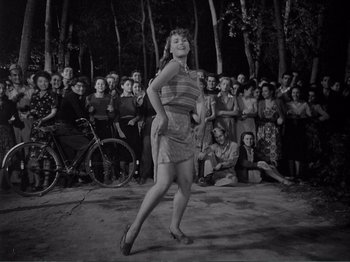 Movie still from “Bitter Rice” (1949), directed by Giuseppe De Santis – An old photo of a woman dancing in front of a crowd; Wide shot, High angle