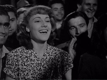 Movie still from “Bitter Rice” (1949), directed by Giuseppe De Santis – An old photo of a woman smiling in a crowd; Medium shot, Low angle