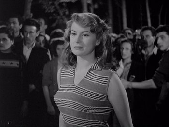 Movie still from “Bitter Rice” (1949), directed by Giuseppe De Santis – A black and white photo of a woman standing in front of a group of people; Medium shot, Over the shoulder angle