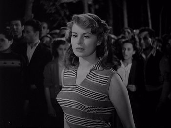 Movie still from “Bitter Rice” (1949), directed by Giuseppe De Santis – A black and white photo of a woman in a crowd of people; Medium shot, Low angle