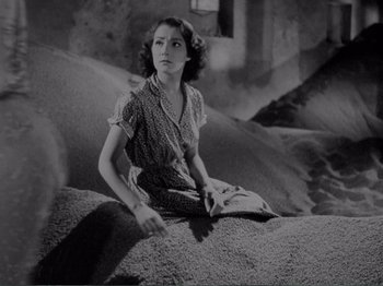 Movie still from “Bitter Rice” (1949), directed by Giuseppe De Santis – A woman sitting on top of a pile of dirt; Medium shot, High angle