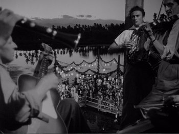 Movie still from “Bitter Rice” (1949), directed by Giuseppe De Santis – A group of men playing music in front of a crowd; Wide shot, Low angle