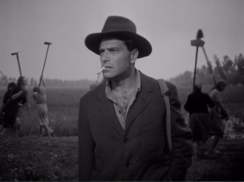 Movie still from “Bitter Rice” (1949), directed by Giuseppe De Santis – A black and white photo of a man in a hat; Medium shot, Low angle