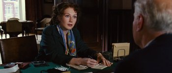 Movie still from “Black Book” (2006), directed by Paul Verhoeven – A woman sitting at a table writing on a piece of paper; Medium shot, Over the shoulder angle
