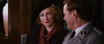 Movie still from “Black Book” (2006), directed by Paul Verhoeven – A woman wearing a hat and a red scarf; Close Up shot, Over the shoulder angle