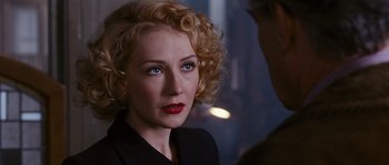 A woman with blonde curly hair wearing a black suit