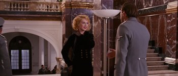 Movie still from “Black Book” (2006), directed by Paul Verhoeven – A woman in a black dress talking to a man in a gray suit; Medium shot, Over the shoulder angle