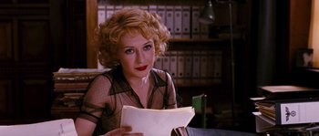 Movie still from “Black Book” (2006), directed by Paul Verhoeven – A woman sitting at a desk holding a paper; Medium shot, Over the shoulder angle