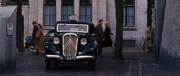 Movie still from “Black Book” (2006), directed by Paul Verhoeven – Two people walk past a taxi cab parked on the side of the road; Wide shot, Low angle