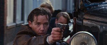 Movie still from “Black Book” (2006), directed by Paul Verhoeven – A man holding a gun while standing next to another man; Close Up shot, Low angle