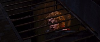 Movie still from “Black Book” (2006), directed by Paul Verhoeven – A woman with red lipstick looking through bars of an iron fence; Medium shot, High angle