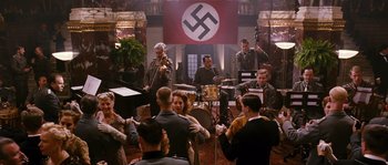Movie still from “Black Book” (2006), directed by Paul Verhoeven – A group of men in military uniforms playing musical instruments in front of a nazi flag; Wide shot, High angle