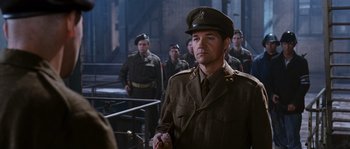 Movie still from “Black Book” (2006), directed by Paul Verhoeven – A group of men standing next to each other in uniform; Medium shot, Over the shoulder angle