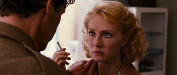 Movie still from “Black Book” (2006), directed by Paul Verhoeven – A woman with a cigarette in her mouth and a man holding a cell phone; Close Up shot, Over the shoulder angle