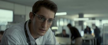 Movie still from “Black Box” (2021), directed by Yann Gozlan – A man with glasses is sitting in an office; Close Up shot, Low angle