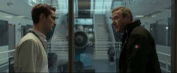 Movie still from “Black Box” (2021), directed by Yann Gozlan – A man standing in front of an escalator looking at himself in a mirror; Medium shot, Over the shoulder angle